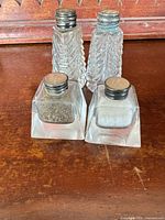 Front view of both pairs of shakers showing shapes and lids