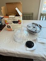 All components laid out: box, plastic dome, black bowl, butter cup, manuals