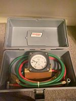 Open carrying case showing gauge, hoses and fittings