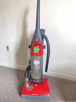 Front view of Dirt Devil Featherlite red upright vacuum with clear dirt cup and hose