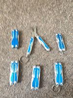Six closed and two open blue Leatherman Squirt multi-tools on carpet