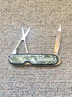 Pocket cutter open showing straight blade, scissors, pearloid scales