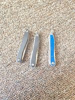 Three Leatherman Style tools closed, showing two gray and one blue units.