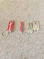 All four keychain multi-tools laid out closed on carpet