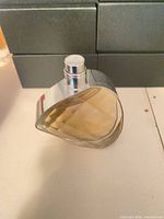 Asymmetrical glass perfume bottle with chrome collar, pale liquid visible