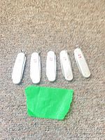 Five closed silver Alox knives on carpet