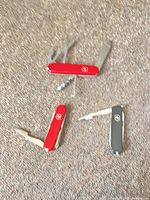 Three Victorinox Swiss Army knives opened to show tools