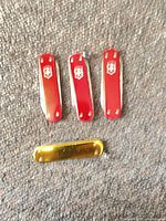 Four Swiss Army pocket knives, three red, one gold