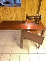 Sewing machine cabinet open with machine visible