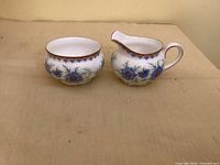 front view of creamer and sugar bowl showing floral pattern and shape