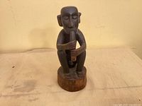 Front view of carved seated figure on round base