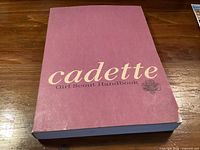 Front cover of Cadette Girl Scout Handbook showing title and wear at bottom corner
