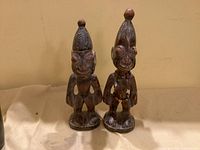 Front view of both carved figures showing overall form, bead adornment and surface condition