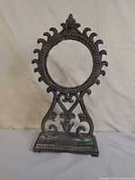 Full view of cast metal stand showing circular frame and ornate base