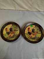 Two rooster motif wall plates displayed face up