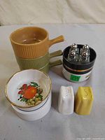 Stacked handled bowls, ramekins, dip bowl, salt and pepper shakers visible