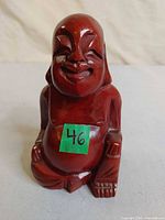 Front view of carved wooden laughing Buddha figure with sticker 46
