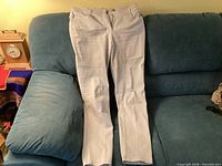 Full frontal view of light grey pants laid flat on sofa