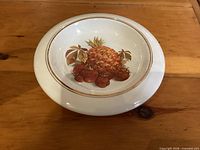 Top view of ceramic bowl showing fruit motif and gold trim