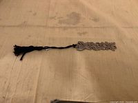 Full view of pewter floral bookmark with black tassel