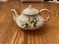 Side view of white ironstone teapot showing floral design and gold trim