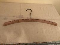 Wooden hanger with printed Woodley Furriers information