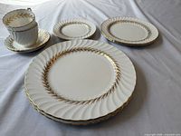 Stack of dinner, salad and bread plates with teacups and saucers, showing overall lot