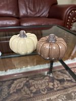 Beige and brown pumpkin shakers on glass table