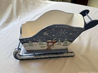 Blue painted wooden sleigh showing side art and runners