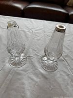 Two cut crystal pedestal salt and pepper shakers, one missing cap