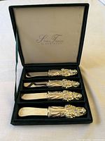 Open presentation box showing four matching nutcracker-handle spreaders