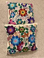 Both embroidered pillows showing full floral designs