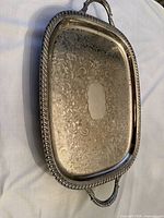 Top view of silver-plated engraved serving tray with handles and gadroon border