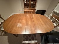 Top view of oval wooden dining table with leaf inserted