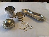 All nine silver-plated serveware pieces arranged on table