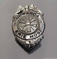Front view of silver tone Gowanda Erie Hose badge