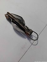 Closed multi-tool showing wood handle and folded fork, spoon, metal loop