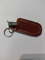 Knife partially inside leather sheath showing keyring attachment