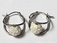 front view of both earrings showing pave crystal balls and silver frames