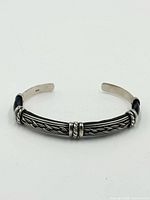 Top view of sterling silver and leather cuff bracelet showing braided central tube and open ends