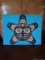 Front view of painted panel showing full hawk-sun motif and color palette