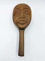 Front view showing carved face on rattle head