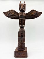 Front view of carved wood totem pole on base
