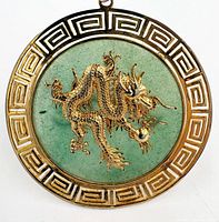 Front view showing jade disk, gold-tone dragon, and Greek key border