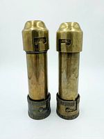 Front view of both brass candle holders showing cylindrical bodies and latch details