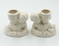 Front view of pair of white glazed cherub candle holders