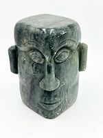 Frontal view showing one carved face, ears and overall green soapstone material