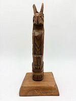 Front view of carved cedar totem pole on base