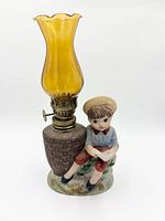 Front view showing porcelain boy reading, basket base, amber chimney