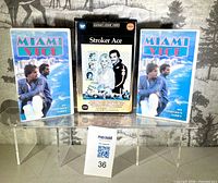 Front view of three VHS tapes: Stroker Ace centered between two Miami Vice Collector's Edition copies